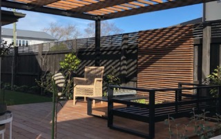 Completed small garden in Fendalton, Christchurch, featuring a Kwila timber pergola, wooden deck, and a striking feature panel, designed for a stylish outdoor living area.